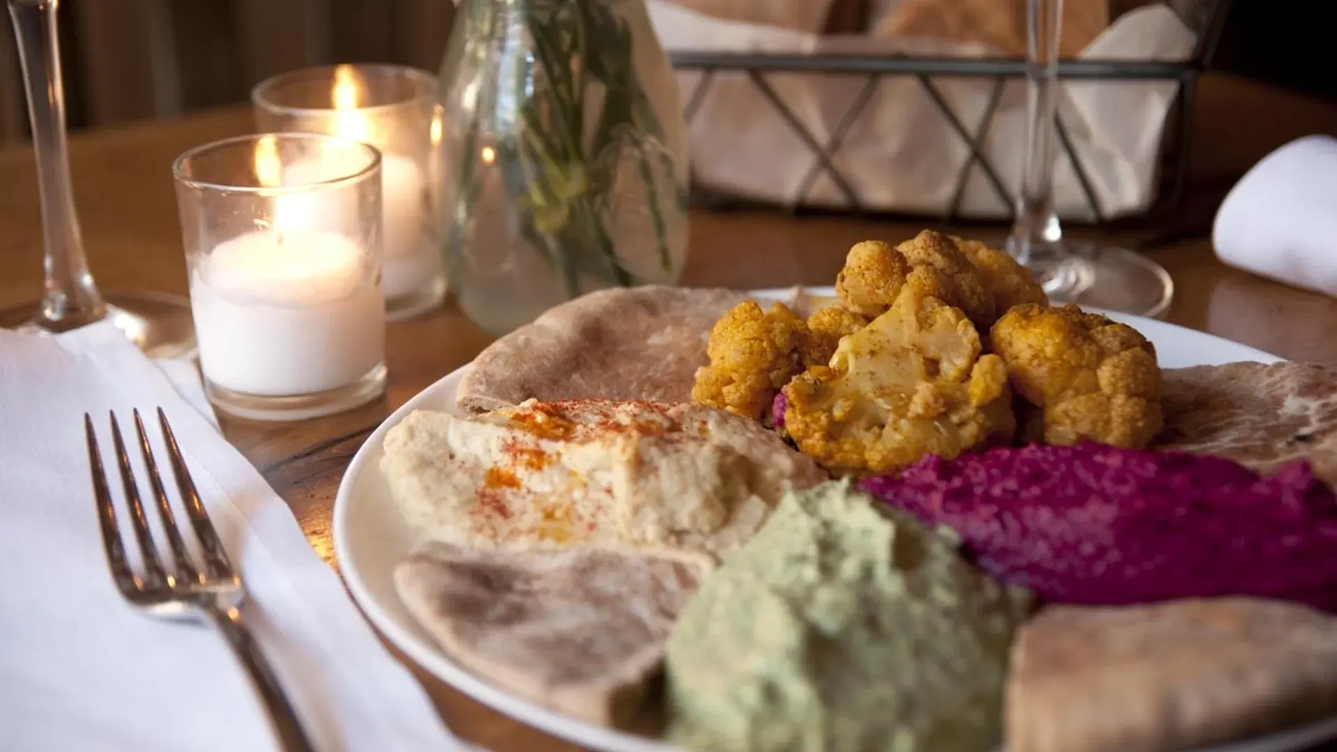 Homemade tapas and dips with pita on a candlelit table